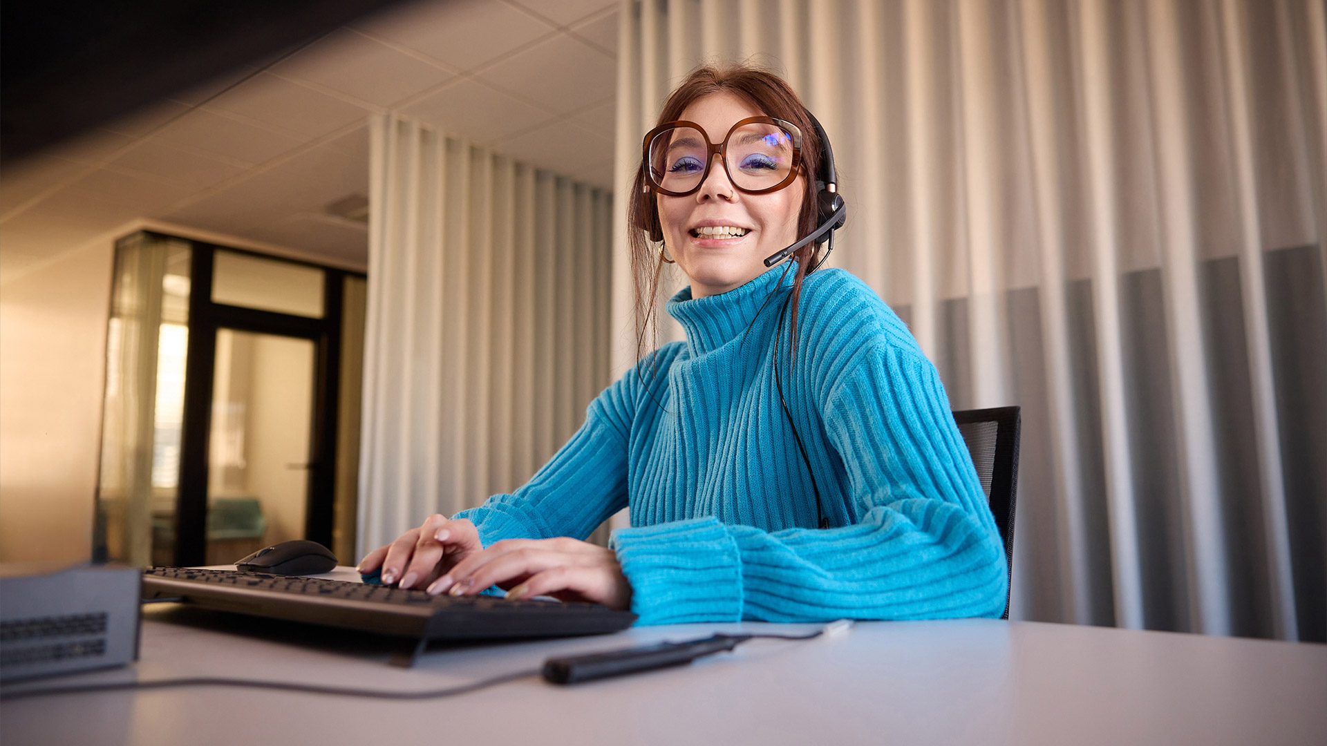 Imagefoto einer TAS Mitarbeiterin mit Headset an einer Tastatur im Call-Center